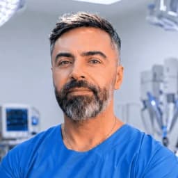 Dr Gabriel Demian en tenue de bloc au bloc opératoire, bras croisés